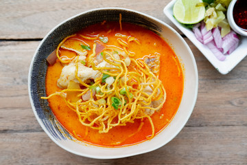 Kao soi noodles soup with chicken on wood table