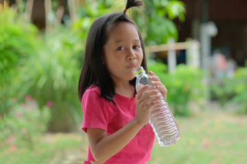 The red shirt girl is drinking water in a nature background