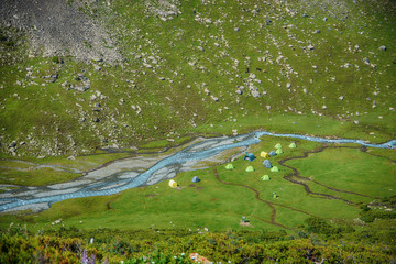 dyllic summer landscape with hiking trail in the mountains with beautiful fresh green mountain pastures and tents camp in the background. National park. Top view.