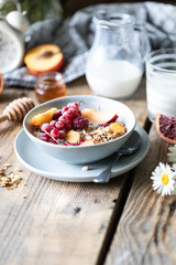 Granola breakfast with berries and fruits and honey and a glass of milk or yogurt on a wooden table. Bouquet of daisies. rustic