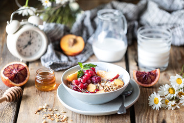 Granola breakfast with berries and fruits and honey and a glass of milk or yogurt on a wooden...