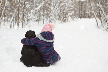 Fototapeta na wymiar Young girl with black Labrador Retriever dog in the snow.