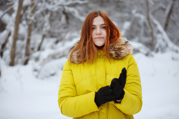 Young, pretty, cheerful red long-haired woman in winter outside.