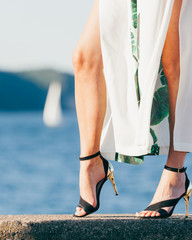 Woman feet in high heels shoes on sea pier