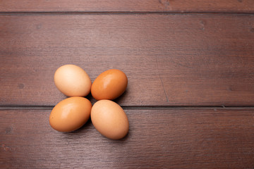 Close up of organic raw chicken eggs in egg box on brown wooden floor background