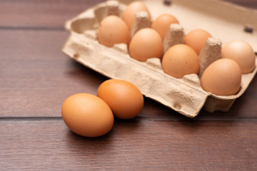 Close up of organic raw chicken eggs in egg box on brown wooden floor background