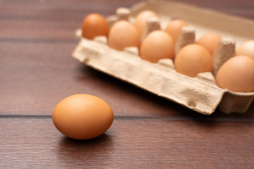 Close up of organic raw chicken eggs in egg box on brown wooden floor background