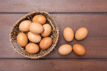 Top view close up of organic raw chicken eggs in basket on brown wooden floor background