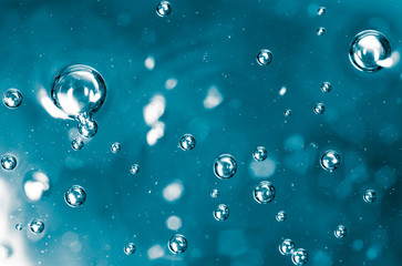 Bubbles of air on the smooth surface of blue water as an abstract background