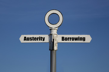 Old road sign with a choice between austerity and borrowing written on it.  Government fiscal policy concept