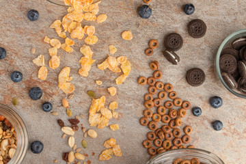 muesli and cereals are scattered with jars of blueberries and sweet cookies on a light background, breakfast background.flat lay? top view