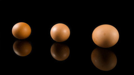 three egg isolated in black with reflection below