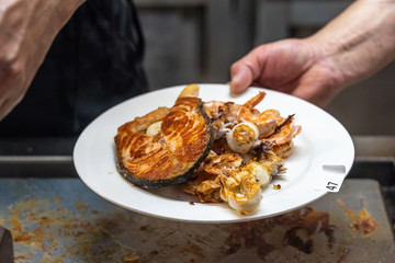 Close up photo of hand holding plate of assorted seafood
