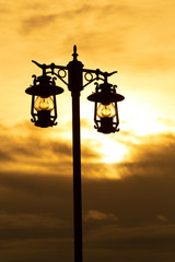 Obraz premium silhouette wrought iron street lamp at sunset