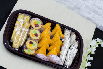 variety of traditional indonesian cake's inside plastic packaging on wood and white brick background