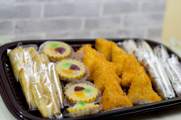 variety of traditional indonesian cake's inside plastic packaging on wood and white brick background