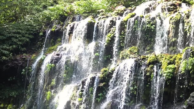 Slow Motion Shot of one of the many beautiful Banyu Wana Amertha Waterfalls gushing off of the mountain in the jungles of Bali, Indonesia.