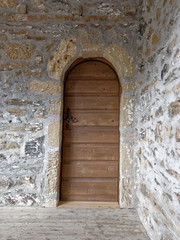 old wooden arched door on stone wall