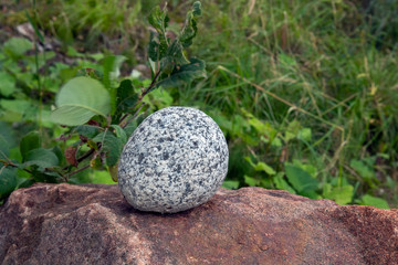 Fototapeta na wymiar Round gray stone on top of brown boulder outdoors