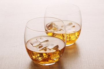 Two glasses with whiskey with ice cubes