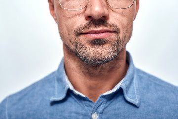 Perfect look. Cropped photo of bearded man in eyewear looking at camera while standing against grey background