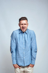 I don't like it. Frustrated young man keeping hands in his pockets and making unhappy face while...