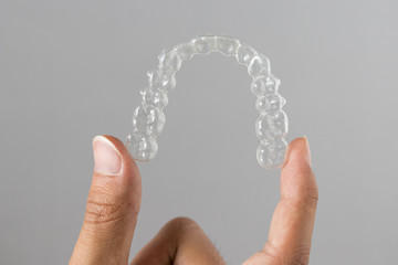 Invisalign braces or invisible retainer on grey background