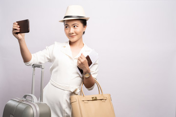 Woman taking selfie on smartphone and holding travel ticket isolated white background