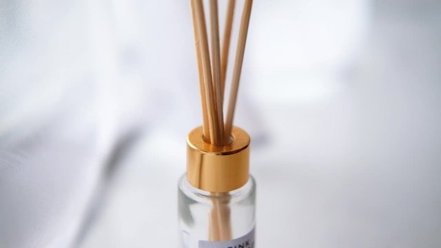 Wooden sticks inserted in a reed diffuser bottle. White environment