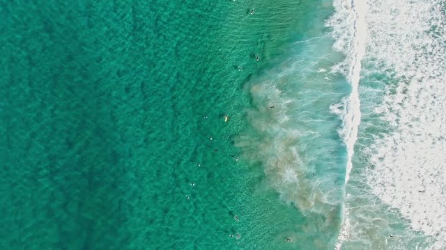 Stunning dynamic 4k aerial bird's eye view of a life saver's fast jet ski driving past surfers in wetsuits waiting for good waves at world famous Bondi Beach, Sydney, New South Wales, Australia. 