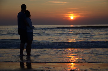 Couple amoureux devant un couché de soleil sur la plage