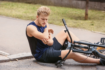 Sporty young man fallen off his bicycle outdoors