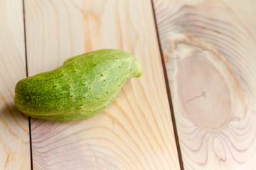 crooked green cucumber on a beautiful wooden panel
