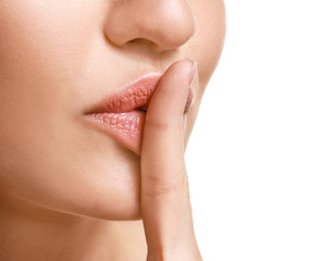 Beautiful young woman showing silence gesture on white background, closeup