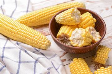 Bowl with raw cut corn cobs on wooden background