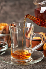 Pouring of hot tea in cup on table