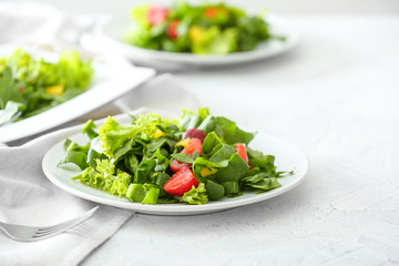 Plates with fresh tasty salad on light table