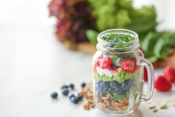 Mason jar with fresh tasty salad on table
