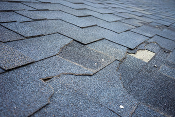 Close up view of bitumen shingles roof damage that needs repair. - obrazy, fototapety, plakaty