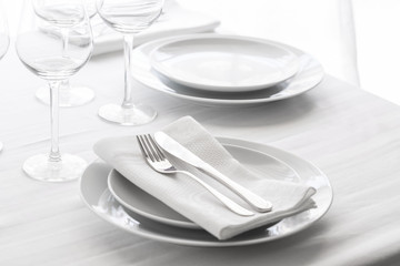 Table setting with white plates, silver cutlery and glasses for elegant festive dinner. Dinning concept background.