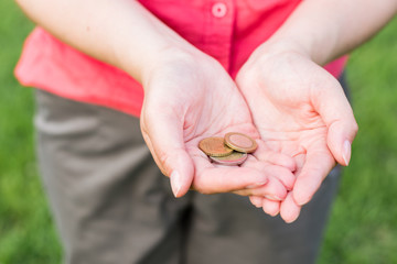 Women hands holding coins, the concept of business, natural green background in summer day
