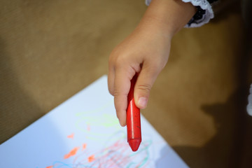 detail of children's hands painting with different colored paints on blank sheets sitting on the floor