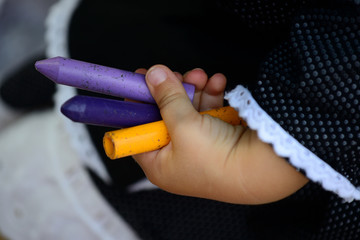 detail of children's hands painting with different colored paints on blank sheets sitting on the floor