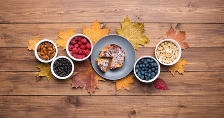 Seasonal autumn background. Frame of maple leaves and a cake over wooden background.