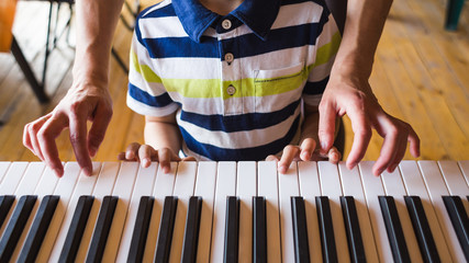 Children's and women's hands on the piano keys. © zhukovvvlad