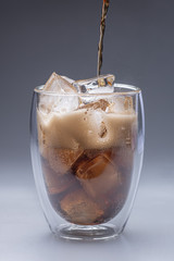 glass of cola with ice isolated on gray background