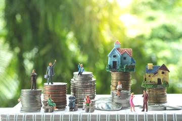 Miniature people: group of business people with rows of coins stack and houses in banking and saving concept.