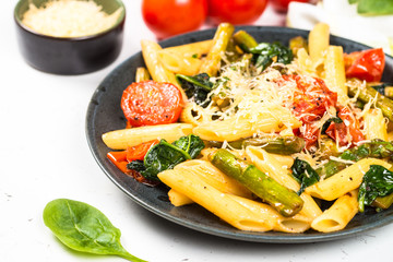 Vegan pasta penne with spinach, asparagus and tomato.