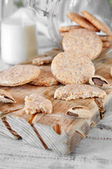 Round almond cookies on the wooden board and a bottle of milk in the background