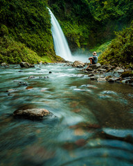 Person watching a beautiful waterfall in Ecuador